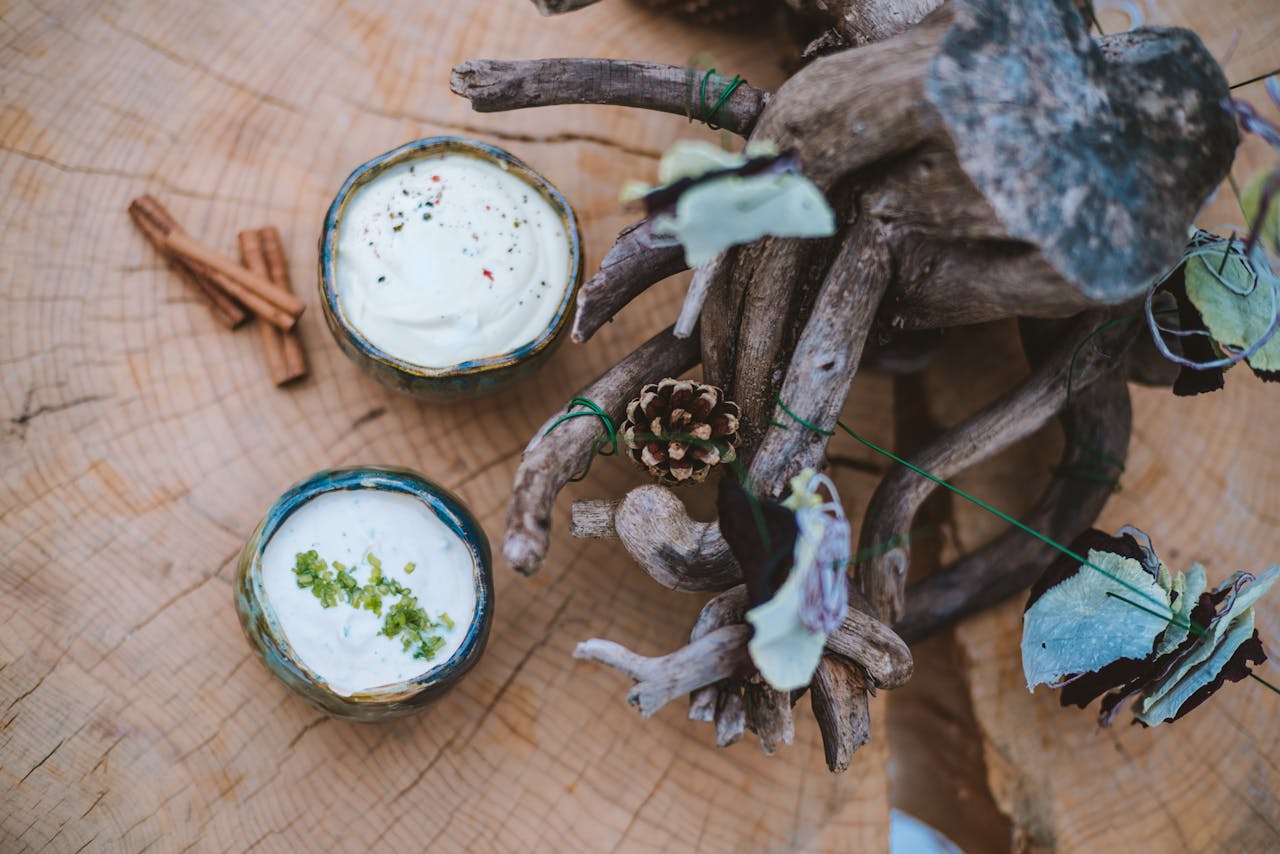 A beautiful rustic table setup featuring creamy dips, cinnamon sticks, and artistic woodwork, exuding a cozy atmosphere.